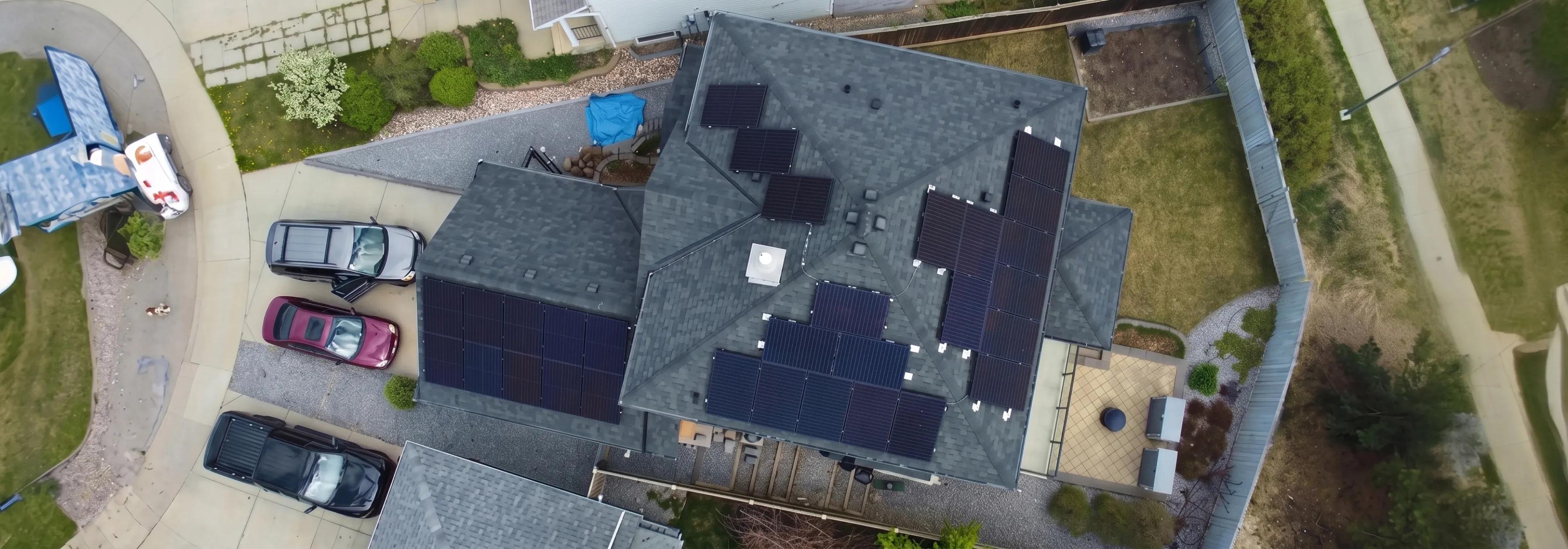 Overhead view of a custom-designed black solar panel system on a residential shingled roof, optimized for Alberta's high-yield sunlight.