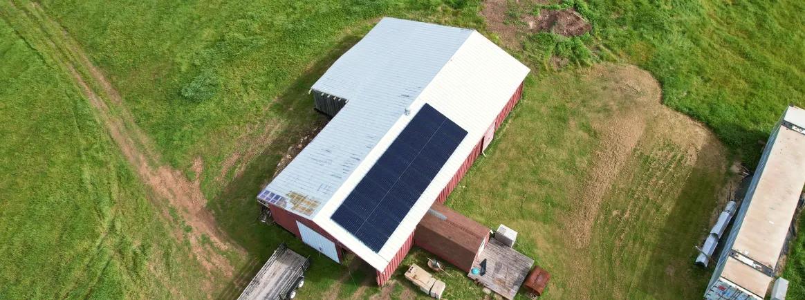 Agricultural solar installation on a metal-roofed farm building in rural Nova Scotia, supporting local industry with renewable energy solutions.