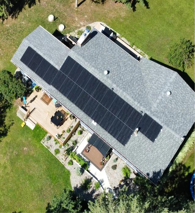 A grid-tied residential solar system powering a modern home, showcasing rooftop solar panels integrated with a heat pump, and a bi-directional utility meter.