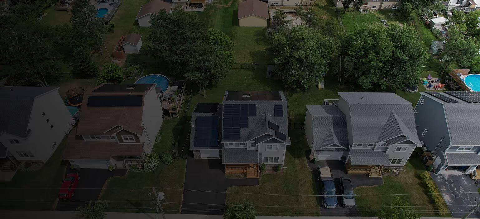 Aerial drone view of a suburban neighborhood featuring residential homes equipped with rooftop solar panel installations protected by Polaron's comprehensive product warranty.