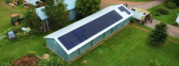 Agricultural solar panel system installed on a green metal-roofed building in rural New Brunswick, supporting local farms with clean, renewable energy.