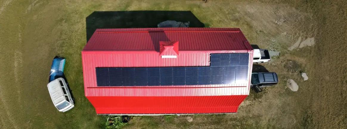 Professional solar panel installation on a red metal rooftop, highlighting specialized mounting solutions for Alberta agricultural and industrial buildings.