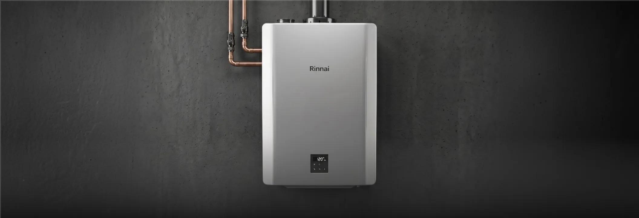 A silver Rinnai wall-mounted tankless water heater unit installed with professional copper piping connections.