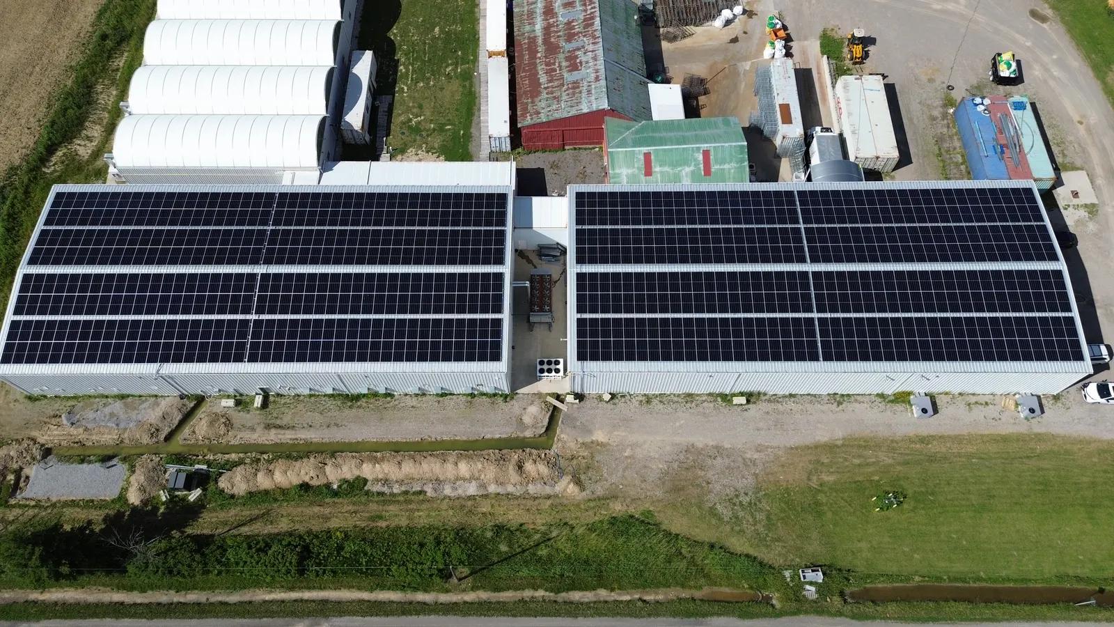 Aerial view of a farm building with ground-mount solar array