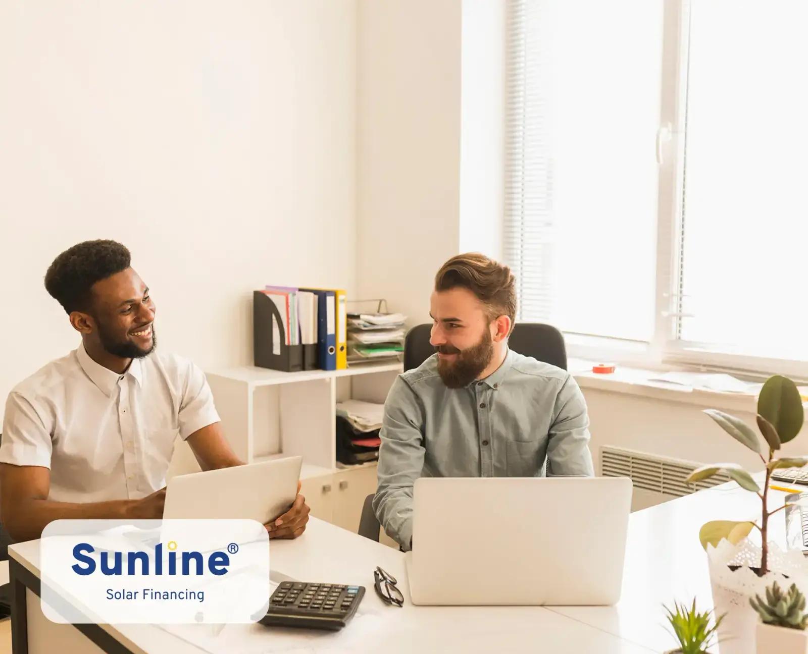 Two colleagues reviewing solar financing options together on a laptop.