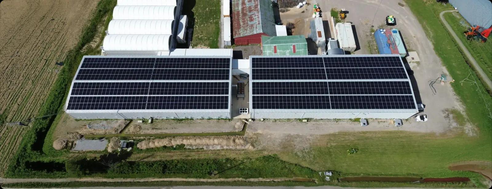 Aerial view of a farm building with solar panels across its roof.