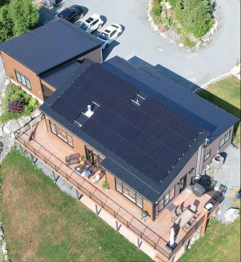 High-angle exterior view of a suburban home with dark monocrystalline solar panels cleanly installed across the roofline.